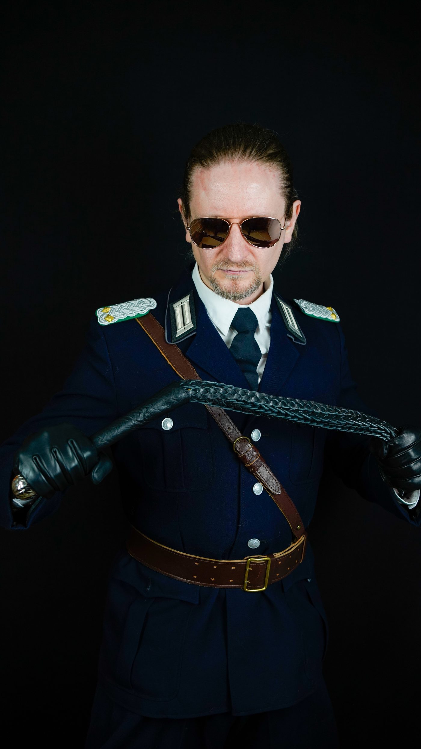 Master Samael in uniform with a flogger